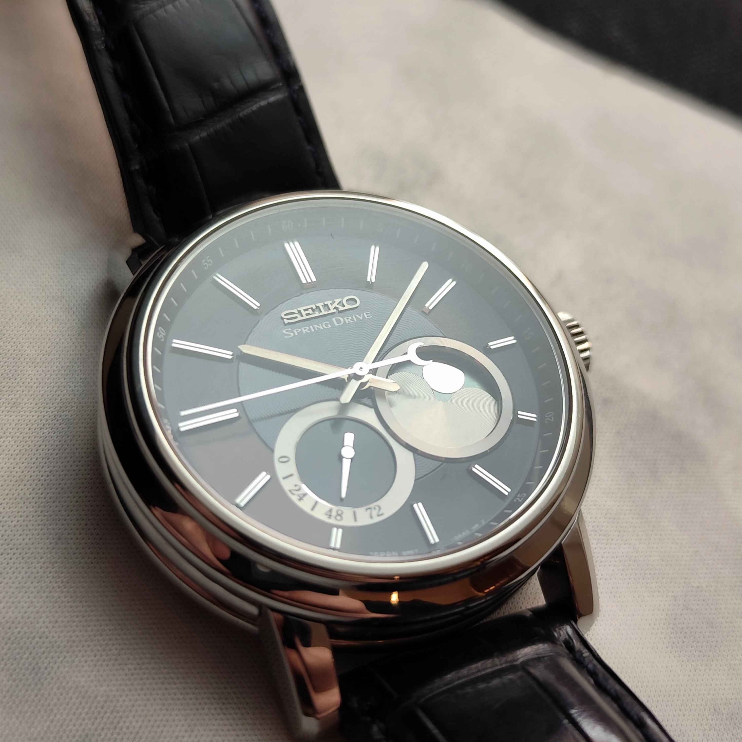 Seiko watch with black leather strap on a gray surface