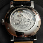 Seiko watch with black strap and visible mechanical components on a dark background