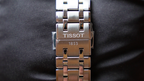 Silver Tissot watch strap on a black background